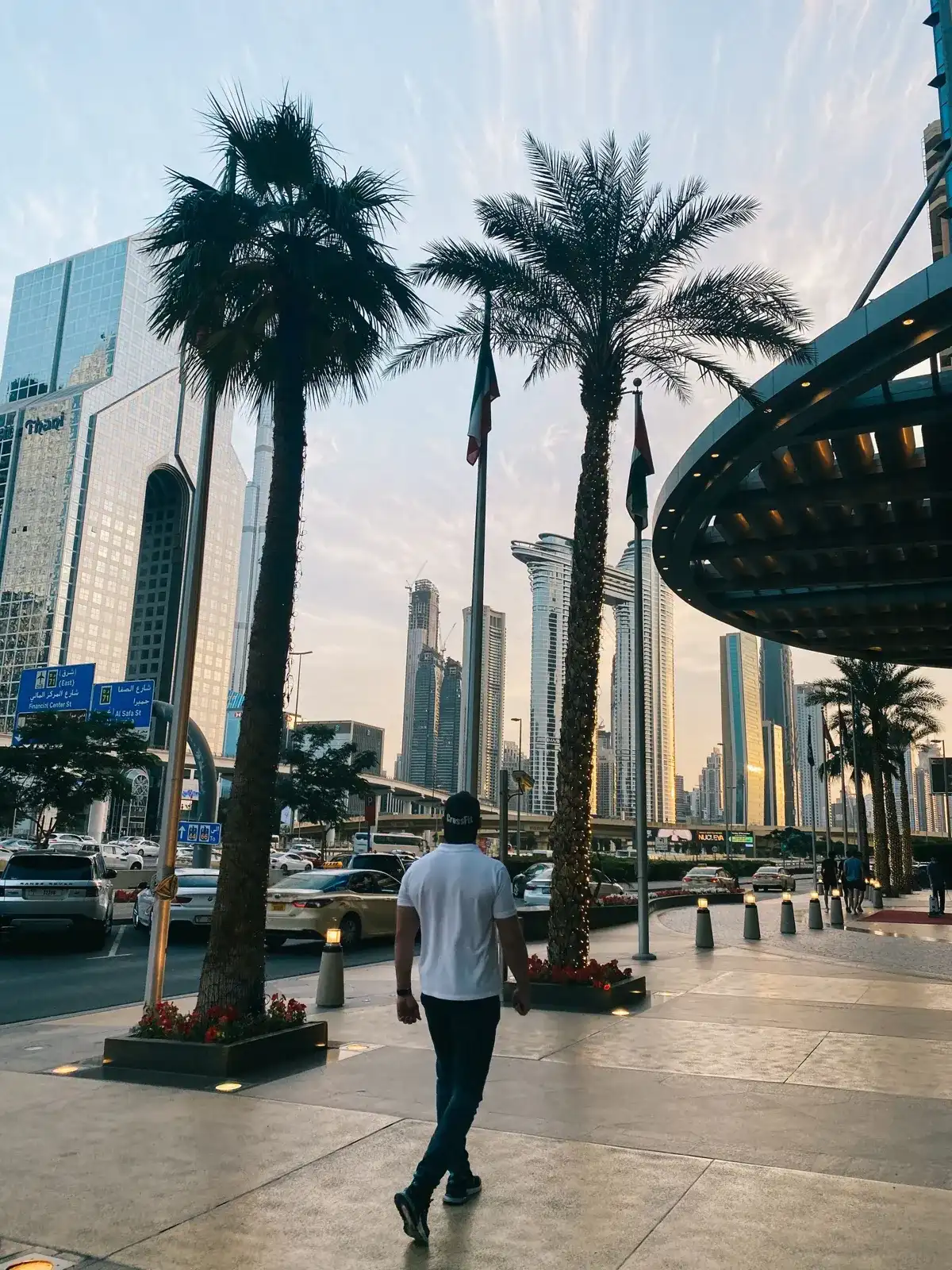 A man walking along a palm-lined street in downtown Dubai