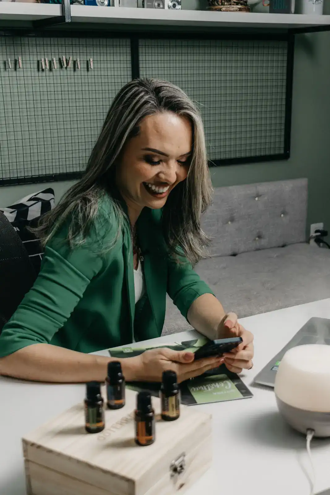 A founder smiling while reading on her phone at her desk