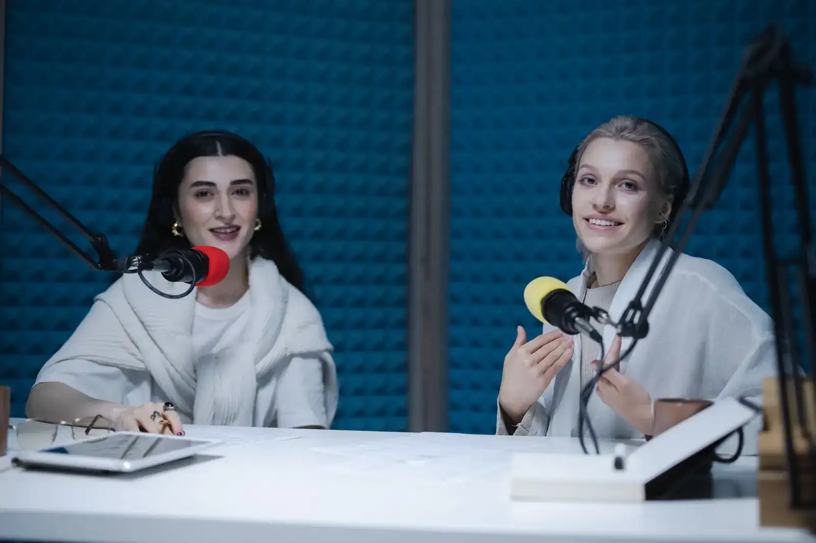 Two hosts recording a conversation with microphones in a studio