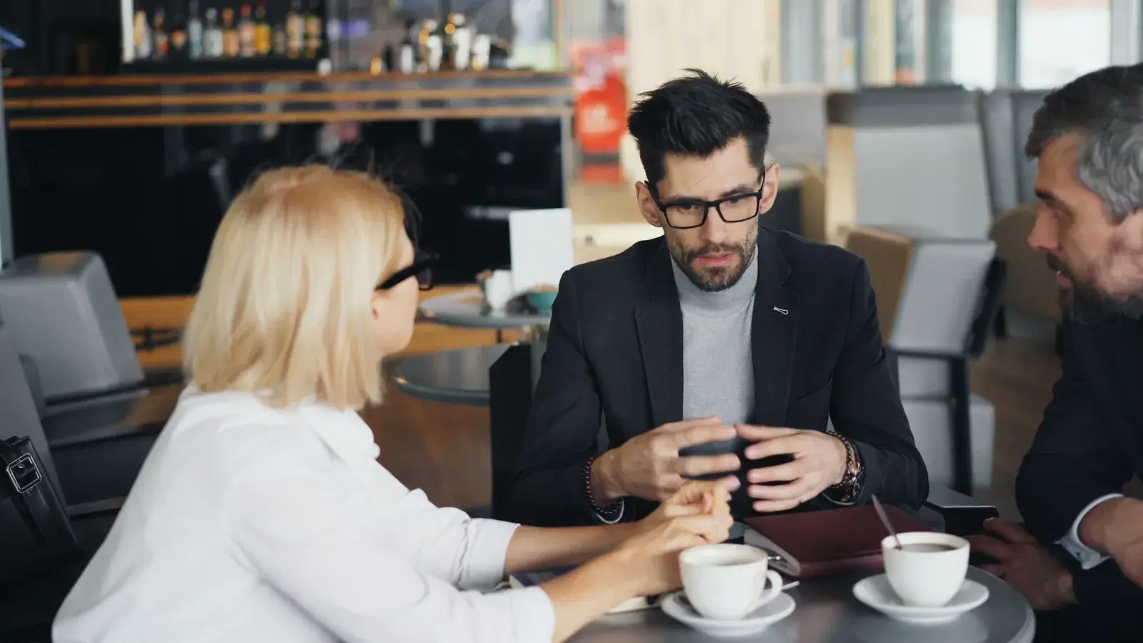 A businesswoman and two businessmen talking at a café table